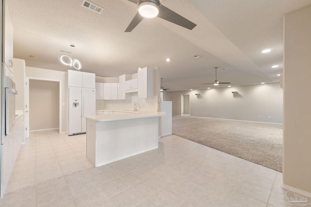 kitchen featuring white cabinets, sink, white fridge with ice dispenser, wall oven, and light colored carpet