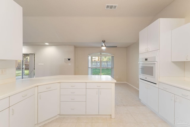 kitchen with kitchen peninsula, white oven, white cabinetry, and ceiling fan