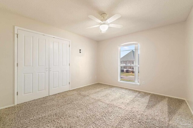 unfurnished bedroom featuring ceiling fan, a closet, carpet, and a textured ceiling