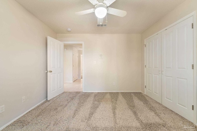 unfurnished bedroom featuring ceiling fan, light colored carpet, a textured ceiling, and a closet