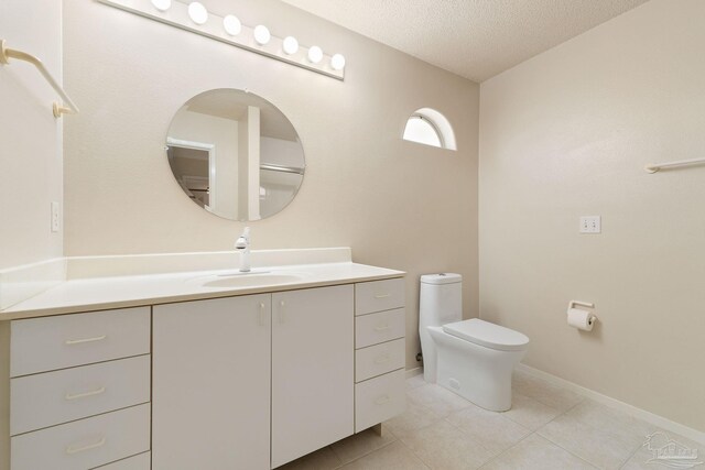 bathroom with tile patterned flooring, vanity, toilet, and a textured ceiling