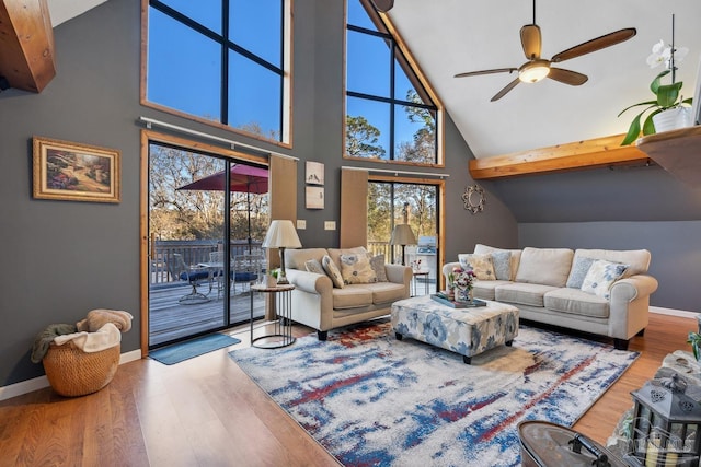 living room with baseboards, high vaulted ceiling, wood finished floors, and a ceiling fan