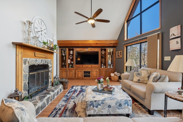 living room featuring a towering ceiling, wood finished floors, a high end fireplace, and a ceiling fan