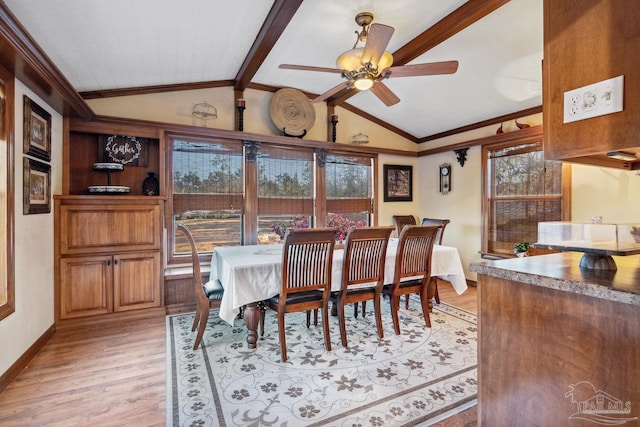 dining room with ornamental molding, lofted ceiling with beams, baseboards, light wood finished floors, and a ceiling fan