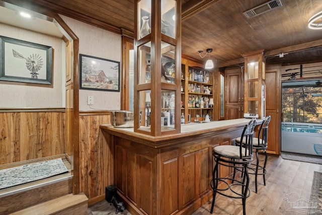 bar featuring a wainscoted wall, visible vents, wooden ceiling, and indoor wet bar