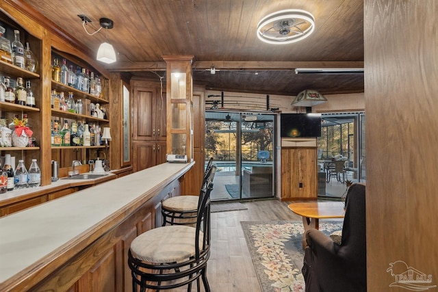bar with bar, wood ceiling, a sink, beamed ceiling, and light wood-style flooring