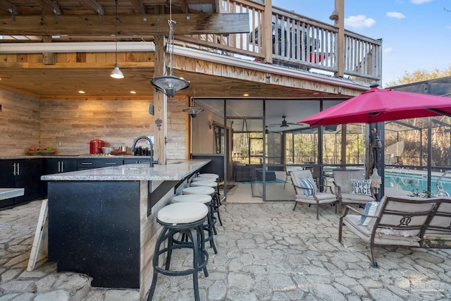 view of patio with glass enclosure, a balcony, outdoor dry bar, and an outdoor pool