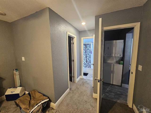 hall featuring stacked washer and dryer and light carpet