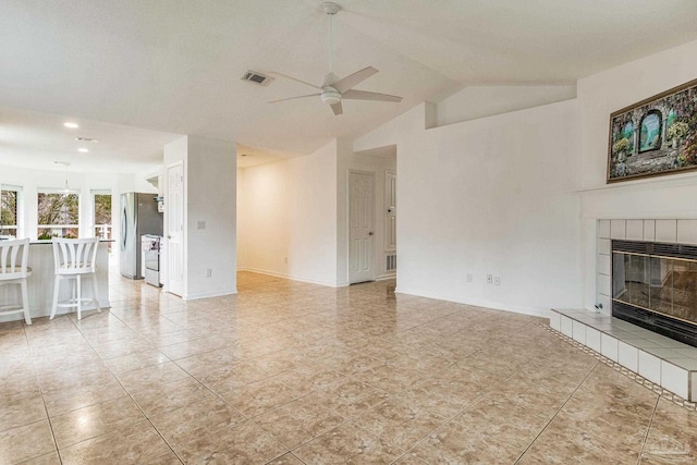 unfurnished living room with light tile patterned floors, ceiling fan, a tile fireplace, and vaulted ceiling