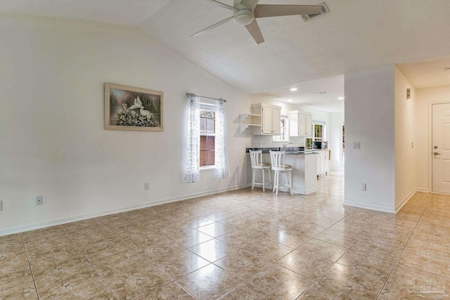 unfurnished living room featuring light tile patterned floors, sink, lofted ceiling, ceiling fan, and a textured ceiling