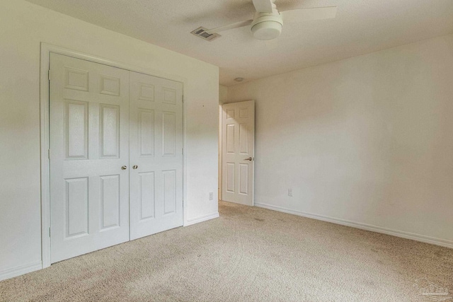 unfurnished bedroom featuring light colored carpet, ceiling fan, and a closet