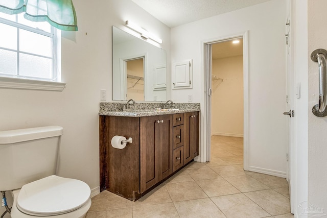 bathroom with tile patterned flooring, toilet, a textured ceiling, and vanity