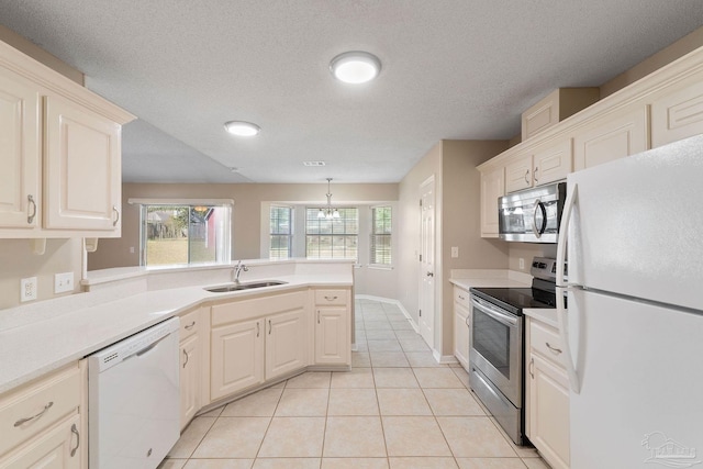 kitchen with hanging light fixtures, stainless steel appliances, sink, light tile patterned flooring, and a textured ceiling