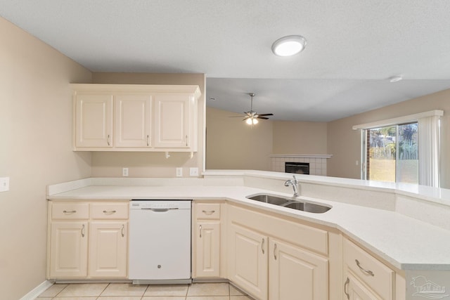 kitchen featuring light tile patterned floors, a textured ceiling, dishwasher, a tile fireplace, and sink