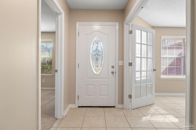 foyer entrance featuring a textured ceiling, plenty of natural light, and light tile patterned floors