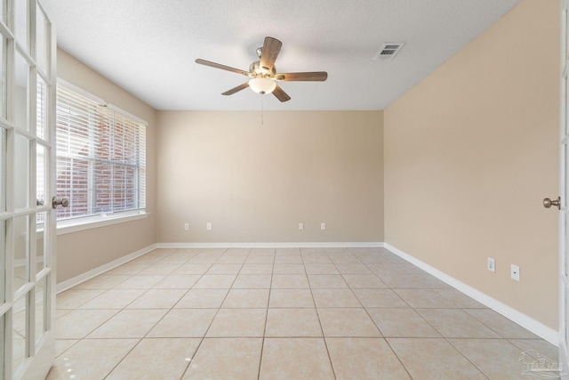 empty room featuring a textured ceiling, ceiling fan, and light tile patterned floors