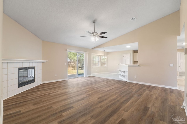 unfurnished living room featuring a textured ceiling, hardwood / wood-style flooring, a tile fireplace, and ceiling fan