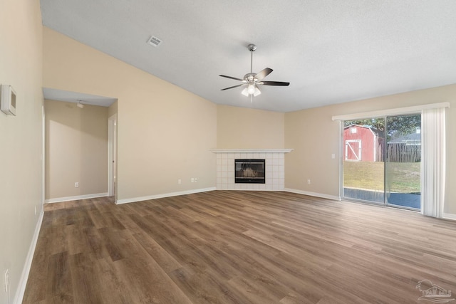 unfurnished living room featuring lofted ceiling, dark wood-type flooring, a textured ceiling, a fireplace, and ceiling fan