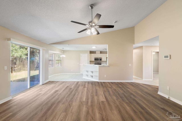 unfurnished living room featuring light hardwood / wood-style floors, lofted ceiling, a textured ceiling, and ceiling fan