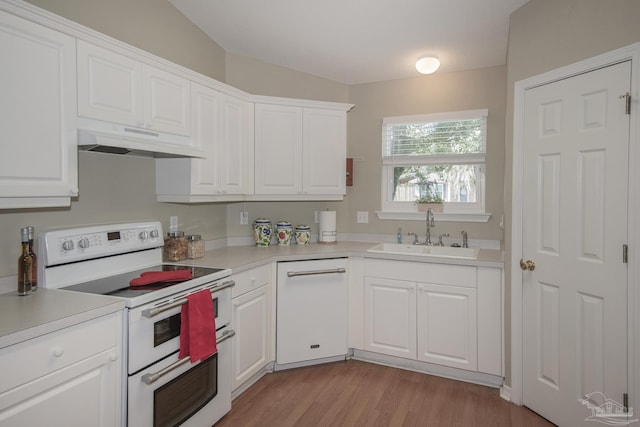 kitchen featuring white appliances, a sink, light countertops, under cabinet range hood, and white cabinetry