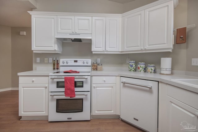 kitchen with under cabinet range hood, white appliances, white cabinets, and light countertops