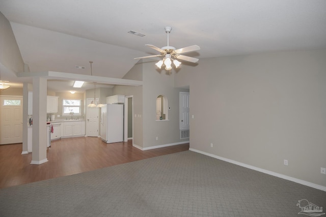 unfurnished living room with visible vents, a sink, wood finished floors, ceiling fan, and vaulted ceiling