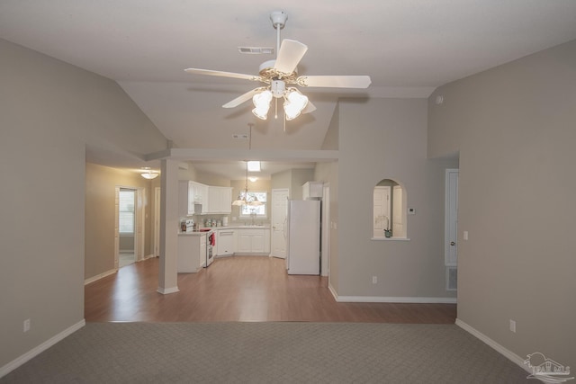 kitchen featuring double oven range, ceiling fan with notable chandelier, freestanding refrigerator, white cabinetry, and a sink