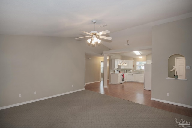 unfurnished living room with wood finished floors, visible vents, baseboards, lofted ceiling, and ceiling fan with notable chandelier