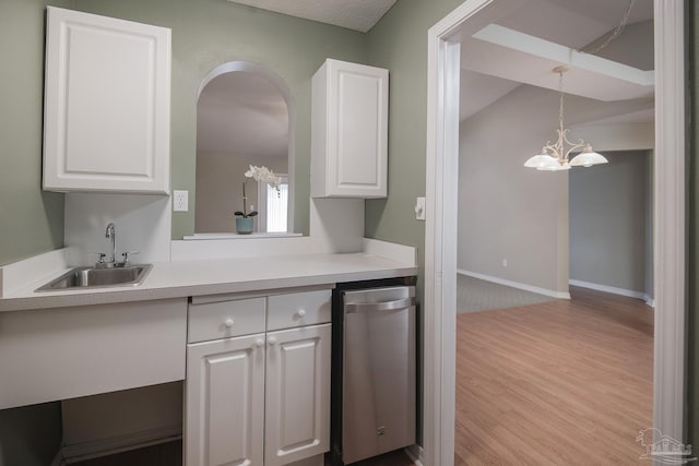 kitchen featuring baseboards, light countertops, wood finished floors, white cabinetry, and a sink