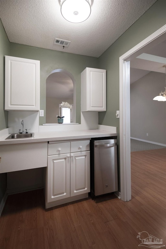 kitchen with visible vents, stainless steel dishwasher, dark wood-style floors, white cabinetry, and a sink