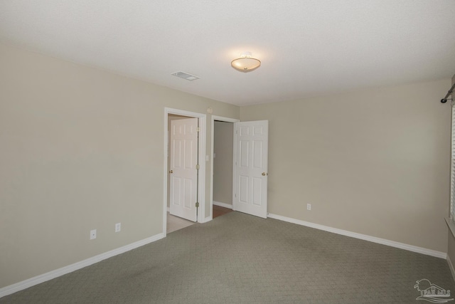 empty room featuring carpet, visible vents, and baseboards