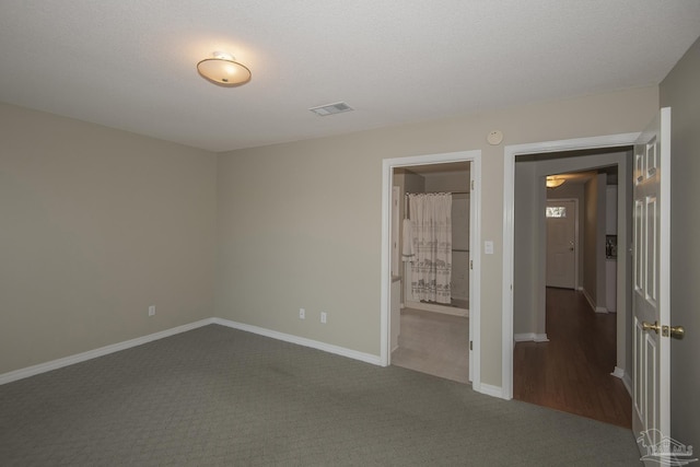 empty room featuring visible vents, baseboards, and dark colored carpet