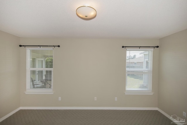 carpeted spare room featuring baseboards and a textured ceiling