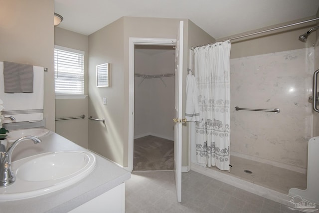 bathroom with double vanity, a shower stall, a walk in closet, and a sink