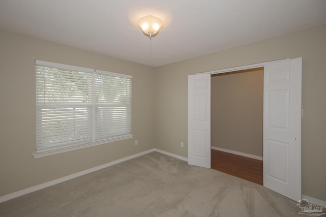 unfurnished bedroom with light carpet and baseboards