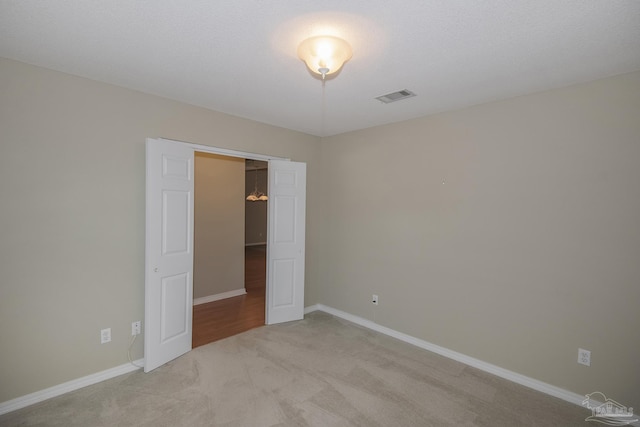 unfurnished bedroom featuring light colored carpet, visible vents, and baseboards