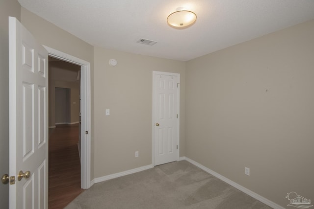 unfurnished bedroom with visible vents, baseboards, light carpet, a closet, and a textured ceiling