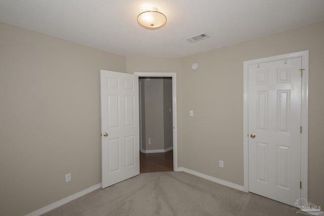 unfurnished bedroom with carpet, visible vents, and baseboards