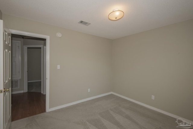 carpeted spare room with visible vents and baseboards