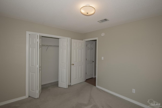 unfurnished bedroom with baseboards, visible vents, carpet floors, a closet, and a textured ceiling