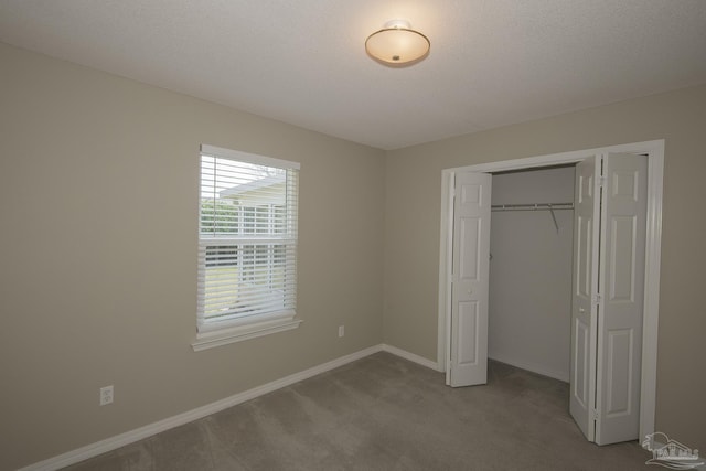 unfurnished bedroom featuring a closet, a textured ceiling, baseboards, and carpet floors