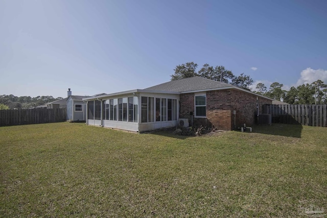 back of house with a sunroom, a lawn, brick siding, and a fenced backyard