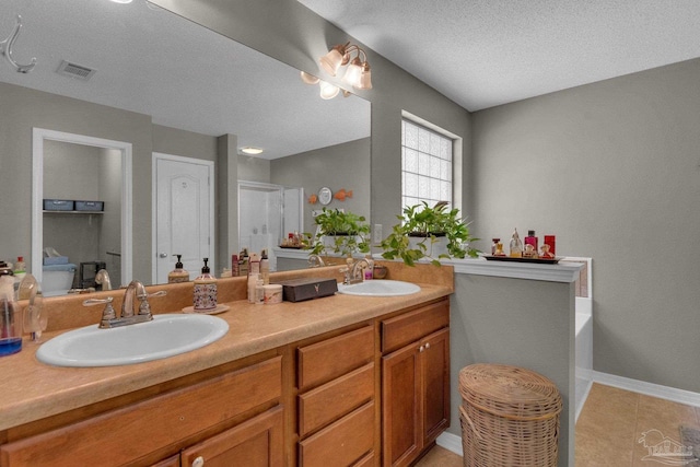 bathroom featuring vanity, a bathtub, tile patterned floors, and a textured ceiling