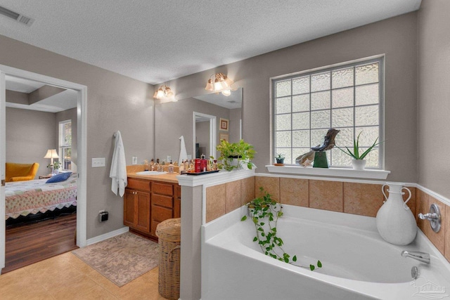 bathroom with vanity, a tub, tile patterned floors, and a textured ceiling