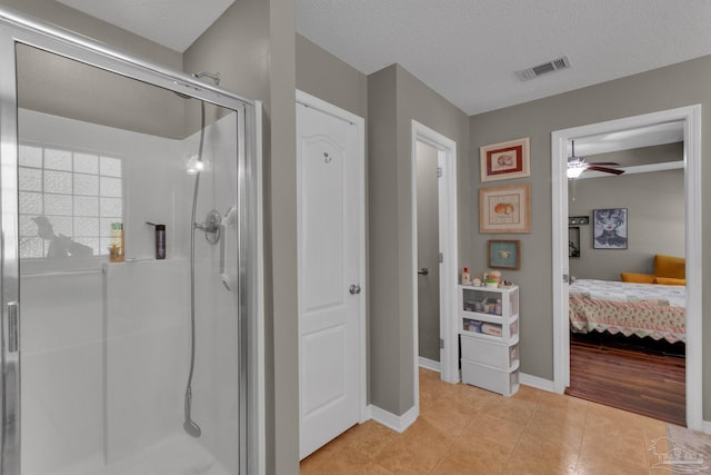 bathroom with an enclosed shower, ceiling fan, tile patterned floors, and a textured ceiling