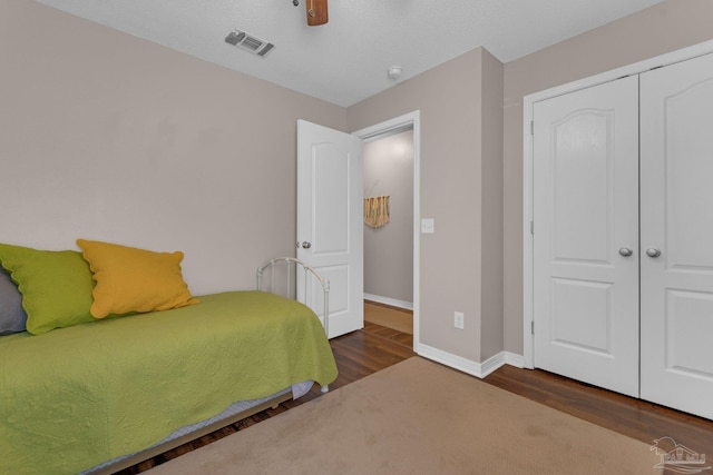 bedroom featuring dark wood-type flooring, a closet, and ceiling fan