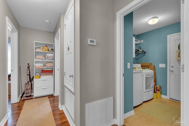 laundry area with hardwood / wood-style floors, washer and dryer, and a textured ceiling