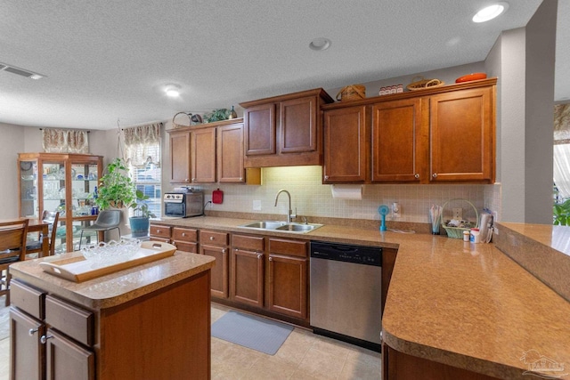 kitchen featuring sink, a center island, tasteful backsplash, a textured ceiling, and stainless steel dishwasher