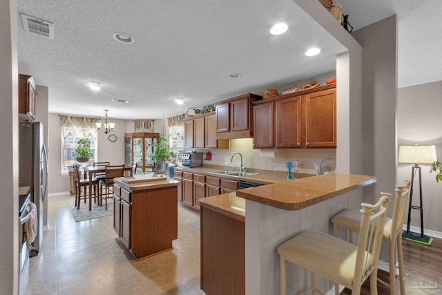 kitchen featuring pendant lighting, sink, a breakfast bar area, a center island, and kitchen peninsula