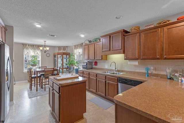 kitchen featuring sink, appliances with stainless steel finishes, a center island, decorative backsplash, and decorative light fixtures